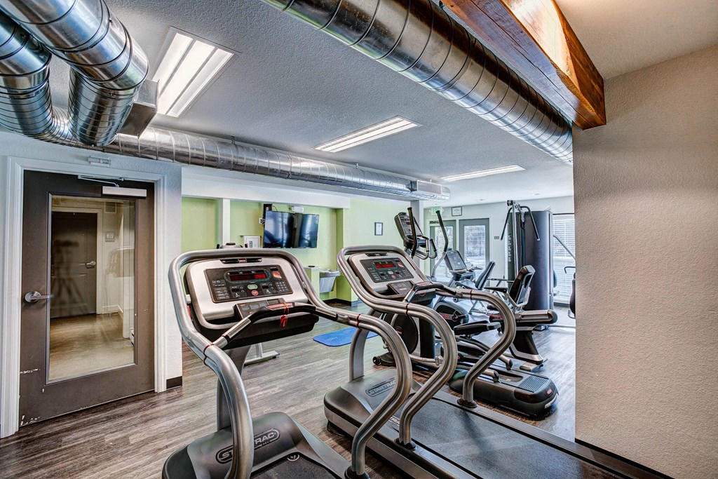 A gym with treadmilers and a door.