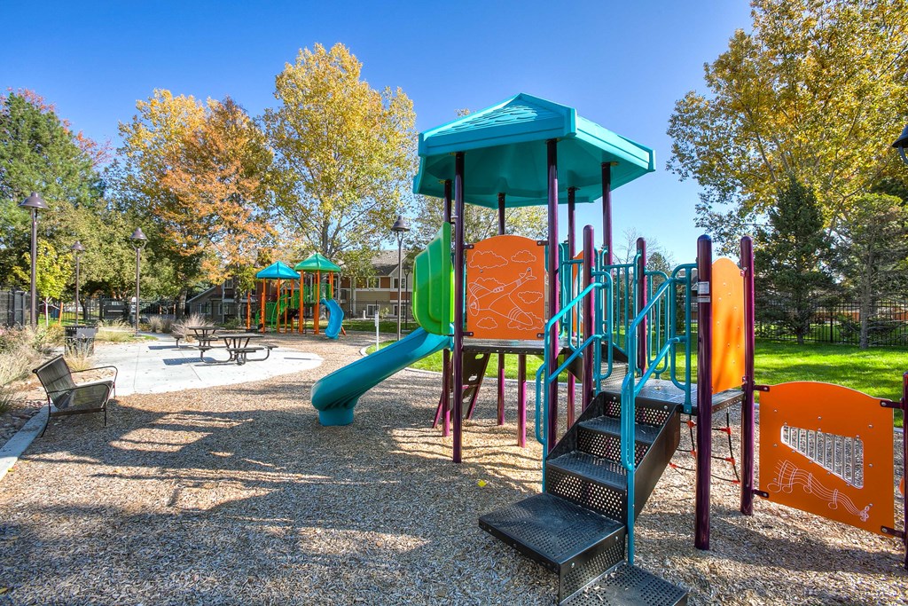 A playground with a blue slide and a green roofed structure.