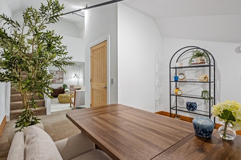 A dining room with a wooden table and a tree in a vase.