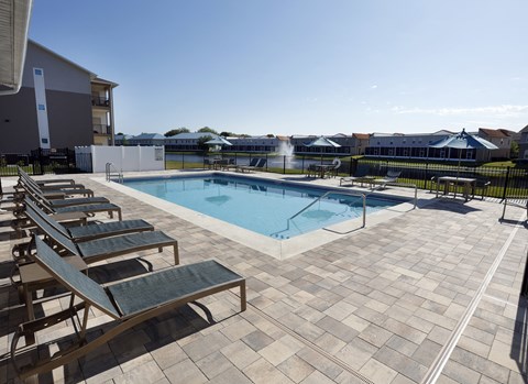 a swimming pool with lounge chairs and a building in the background