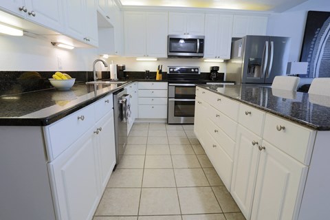 a large kitchen with white cabinets and black counter tops