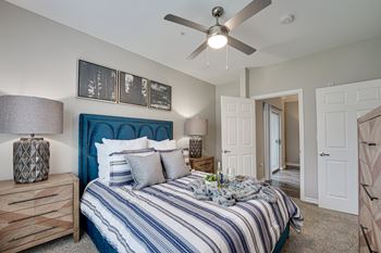 A bedroom with a blue headboard and striped bedspread.