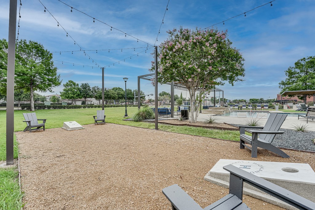 a park with benches and a grassy area with a sprinkler system in the background at Highland Luxury Living Apartments, Lewisville, TX