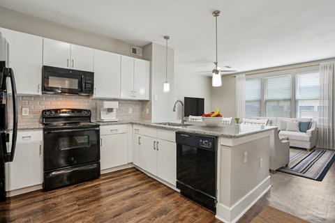 A modern kitchen with white cabinets and black appliances.