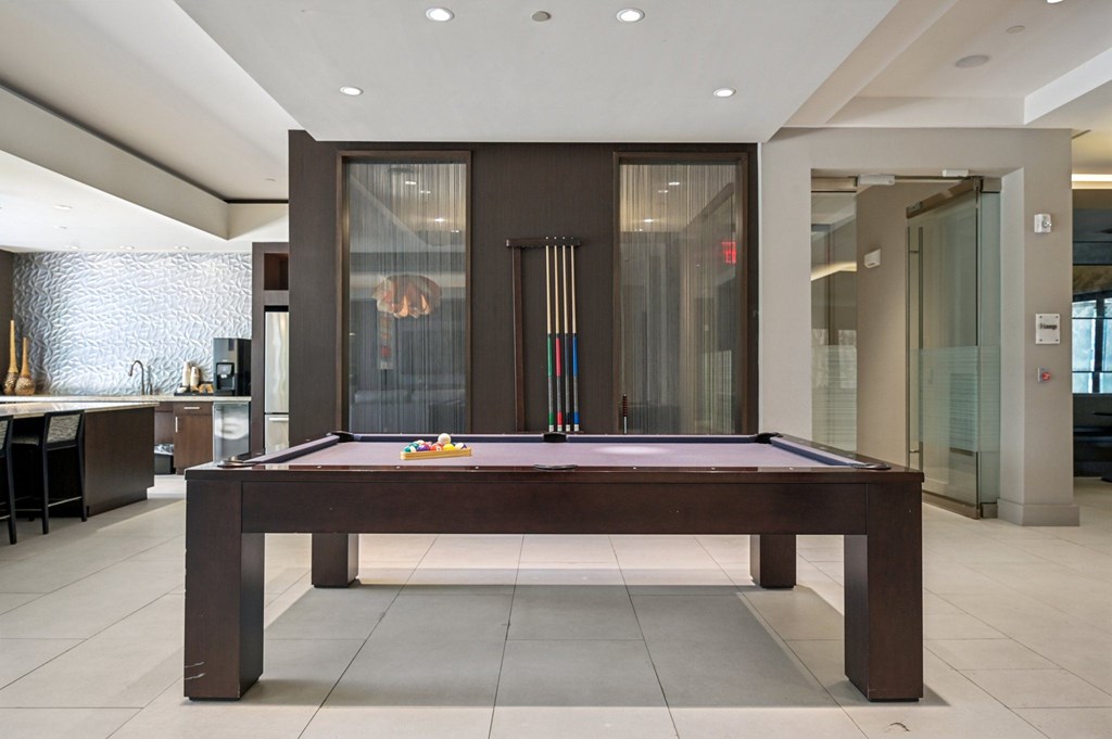 A pool table in a room with a glass door at Everra Midtown Park Apartments, Dallas, Texas