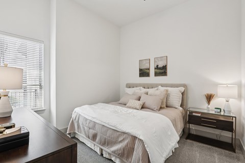 A bedroom with a large bed and a nightstand with a lamp.