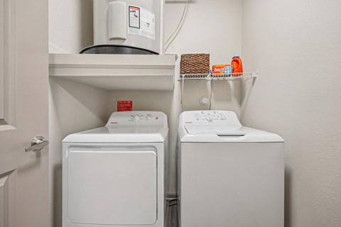 A white dryer and washer are on a shelf in a laundry room.