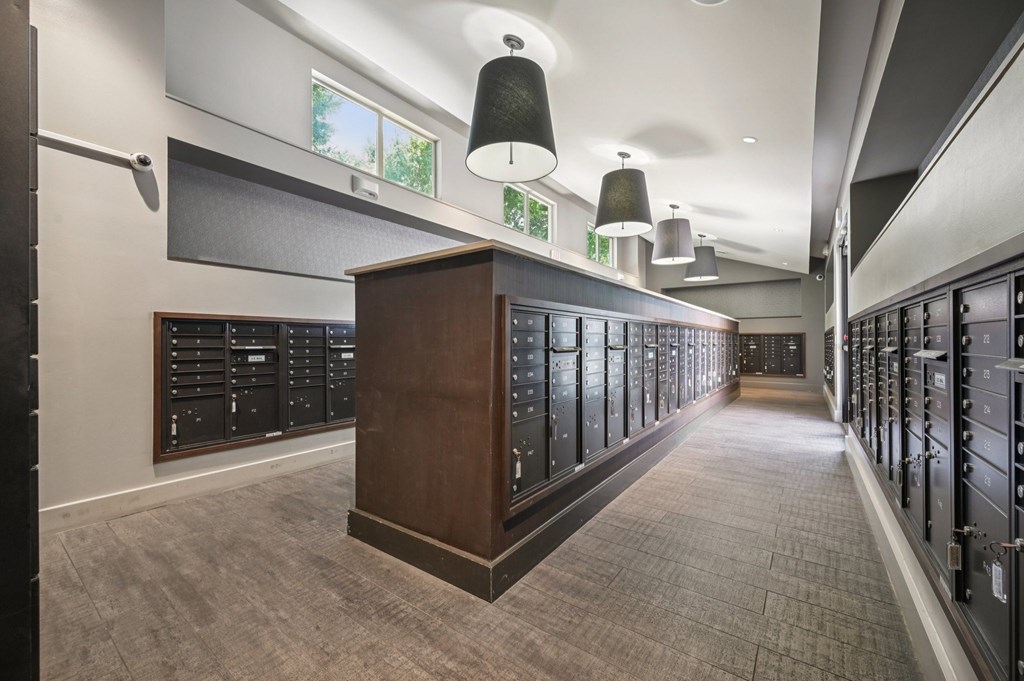 A long hallway with a row of lockers on the right and a wooden cabinet in the middle at Everra Midtown Park Apartments, Dallas