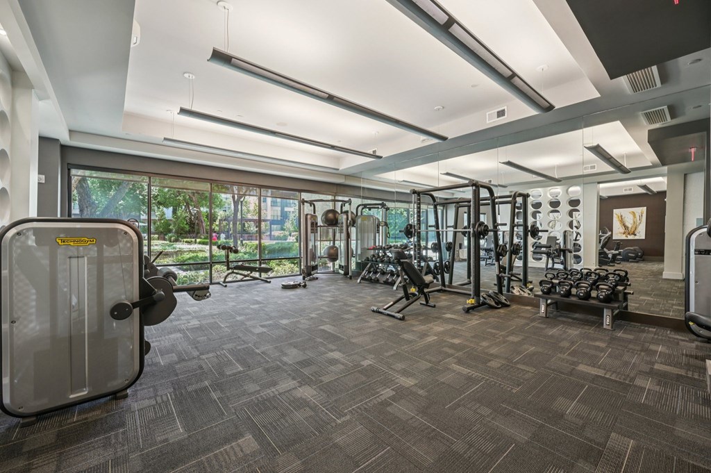 A gym with a variety of equipment including treadmills, weights, and exercise machines at Everra Midtown Park Apartments, Texas