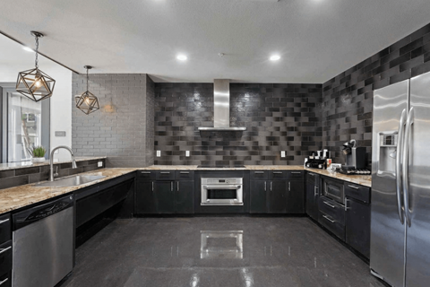 A modern kitchen with black cabinets and a stainless steel refrigerator.