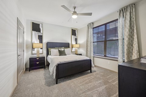 A bedroom with a bed, nightstand, and window.