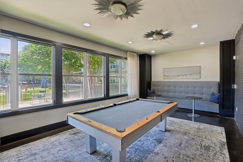 A pool table in a room with a view of the outside.