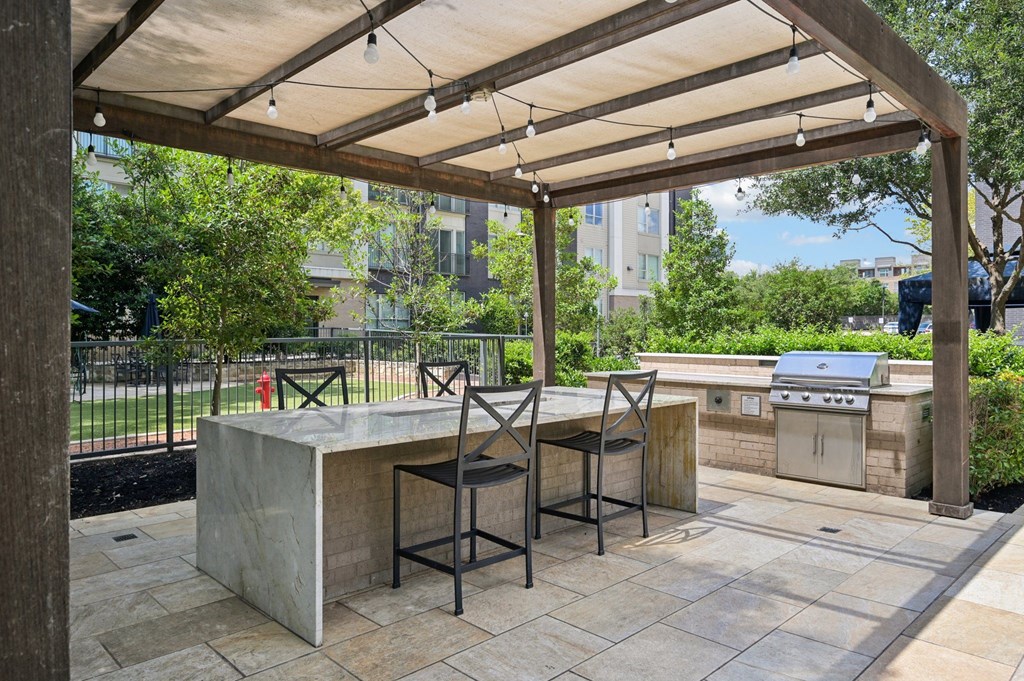 A patio with a table and chairs under a canopy at Everra Midtown Park Apartments, Texas