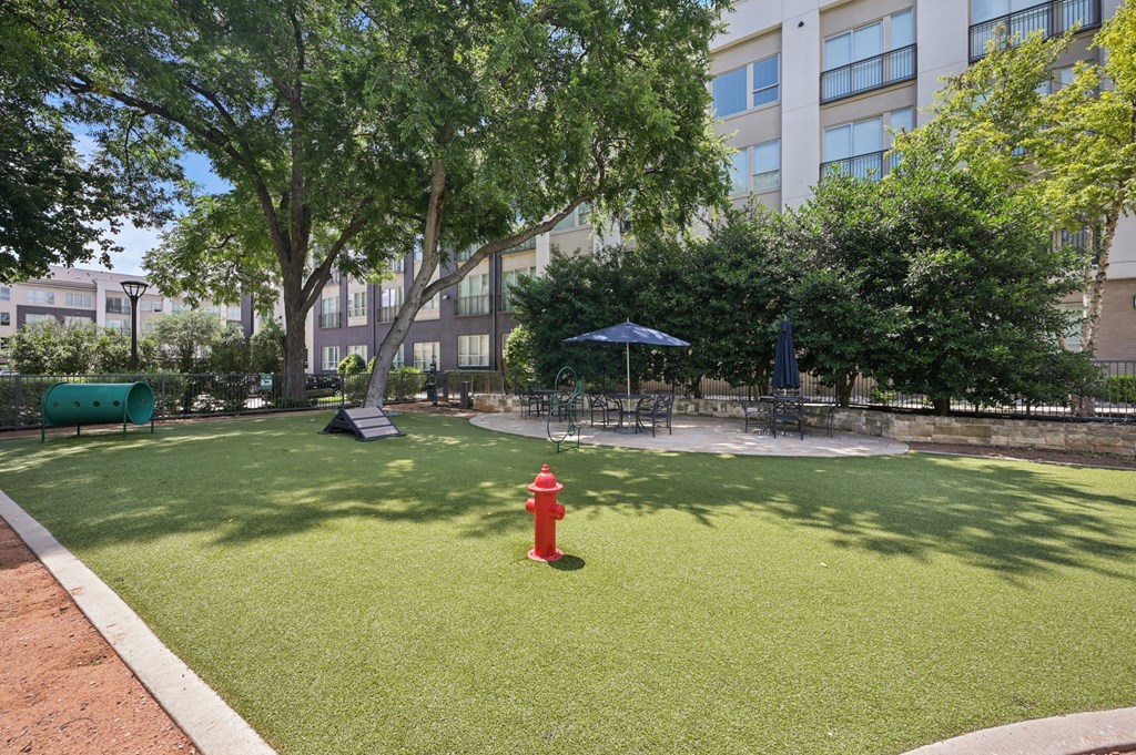 A red fire hydrant sits in the middle of a green lawn at Everra Midtown Park Apartments, Texas, 75231