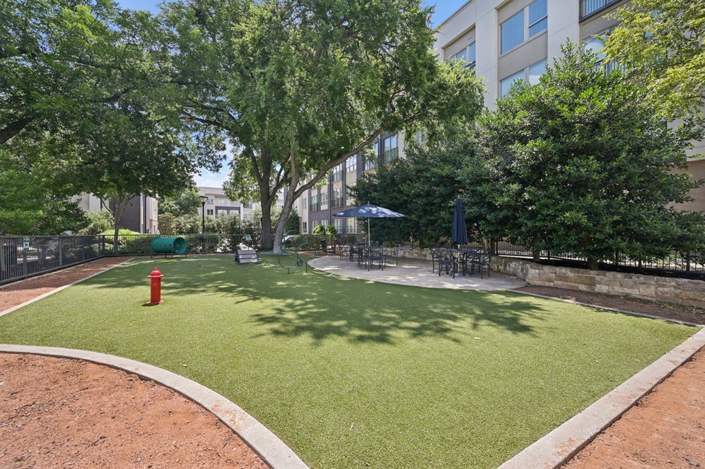 A park with a red fire hydrant and a green lawn at Everra Midtown Park Apartments, Dallas
