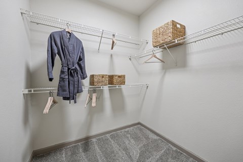 A white closet with a blue robe hanging on a rail.