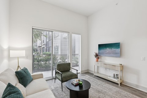A living room with a white couch, a green chair, a coffee table, and a painting on the wall.