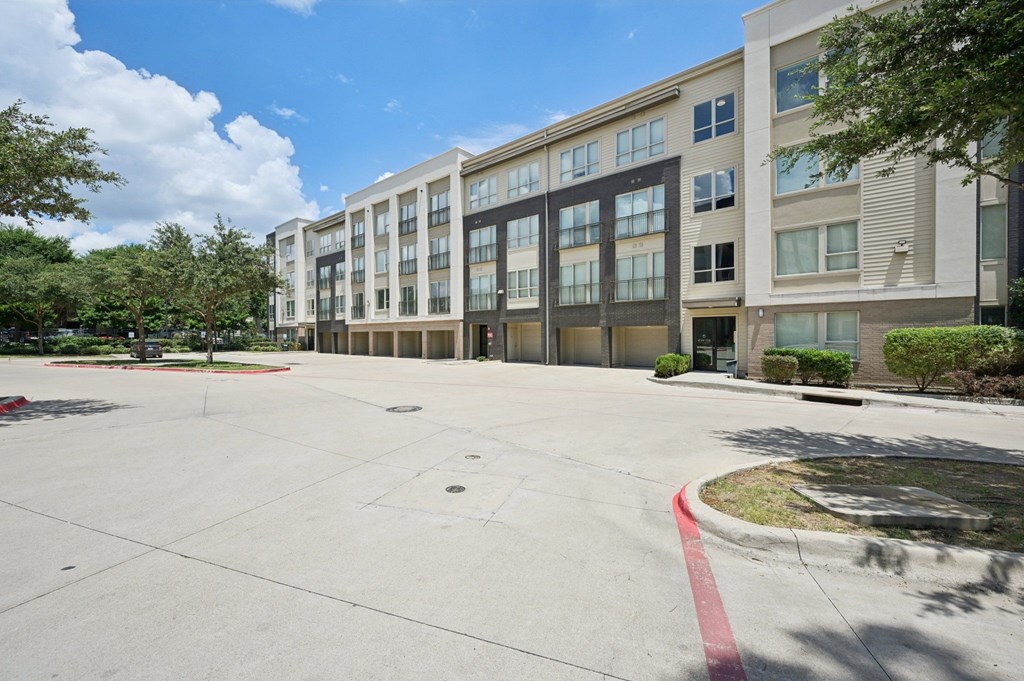 A large, empty parking lot in front of a multi-story building at Everra Midtown Park Apartments, Dallas 75231