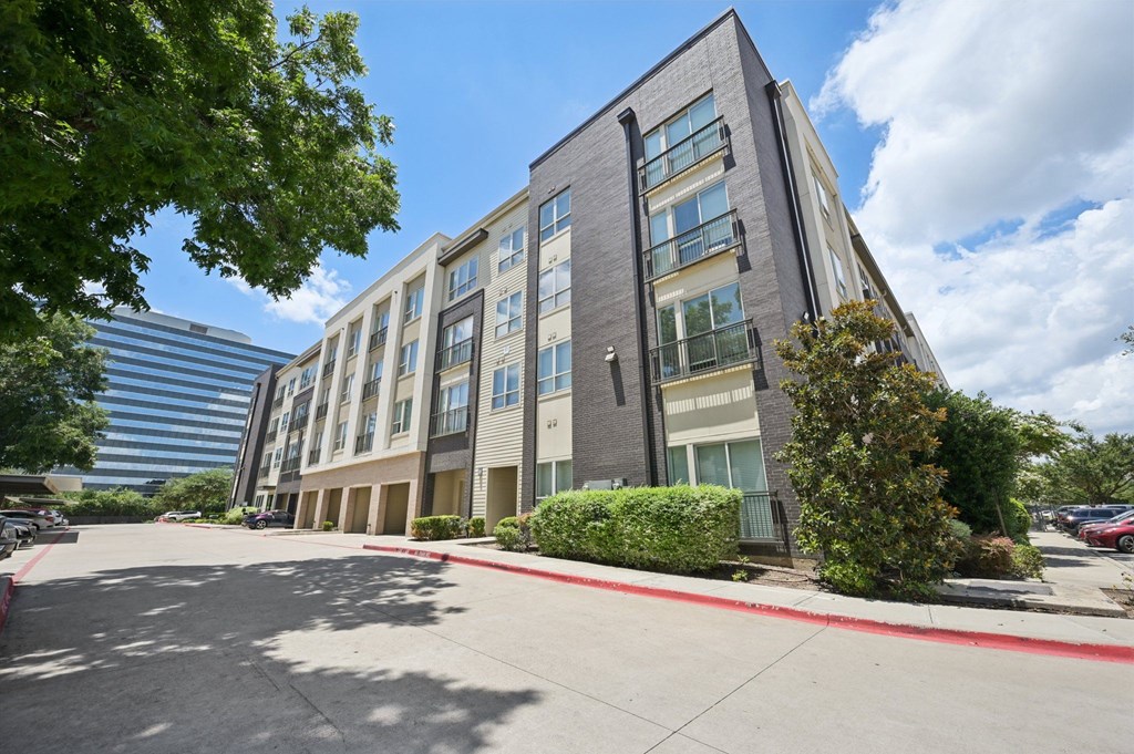 A modern multi-story building with a parking lot in front at Everra Midtown Park Apartments, Dallas, TX, 75231