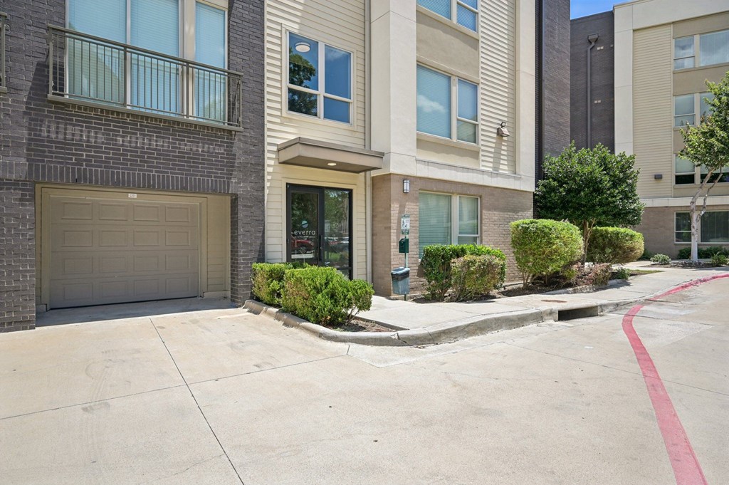 A building with a garage door and a red line on the sidewalk at Everra Midtown Park Apartments, Dallas, Texas