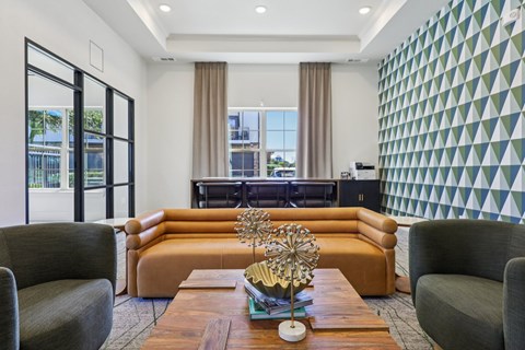 A living room with a brown sofa, a grey armchair, and a wooden coffee table with a gold sculpture on it.