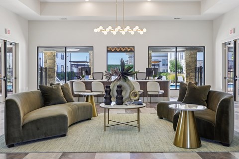 A modern living room with a large grey sofa, a round gold table, and a chandelier.