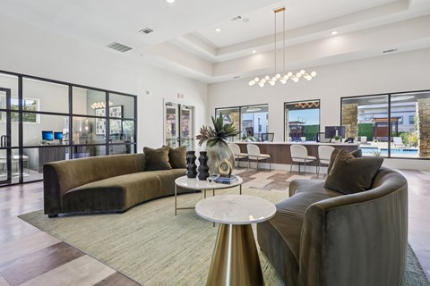 A modern living room with a large sectional sofa, a coffee table, and a large window with a view of the city.