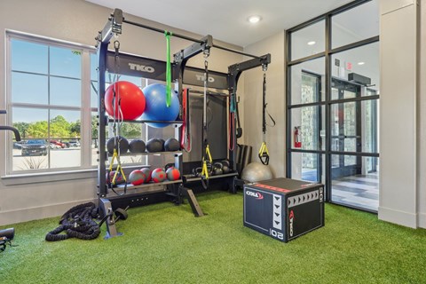 A gym room with a TRX suspension trainer, a weight bench, and a ball suspended from the ceiling.