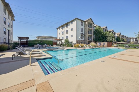 A swimming pool surrounded by a concrete floor and a metal fence.