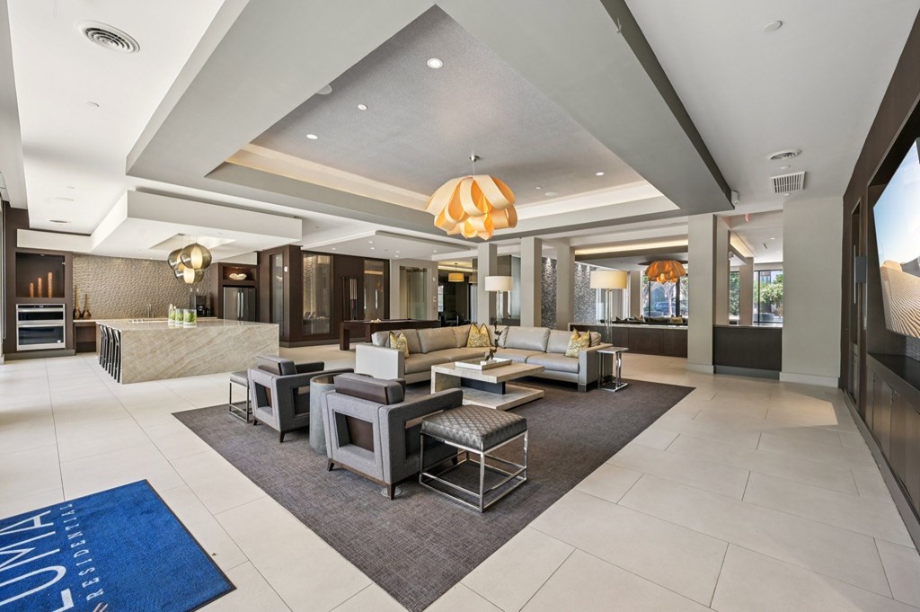 A spacious living room with a large grey sofa set and a grey rug at Everra Midtown Park Apartments, Dallas, Texas