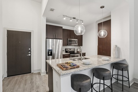A modern kitchen with a granite countertop and stainless steel appliances.