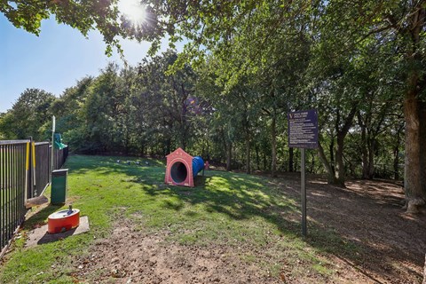A dog house sits in a grassy area next to a sign.