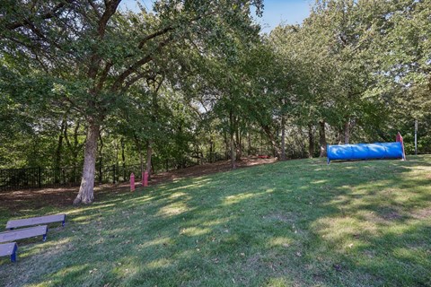 A park with a blue inflatable object and trees.