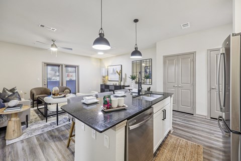 A modern kitchen with a black countertop and stainless steel appliances.