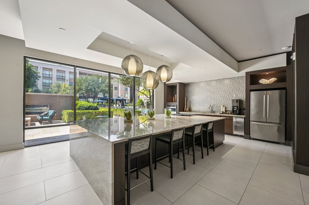 A modern kitchen with a long island and chairs at Everra Midtown Park Apartments, Dallas 75231