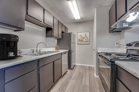 A kitchen with a black fridge and a black coffee maker.