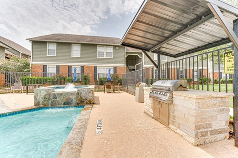 A pool and hot tub area in front of a house.