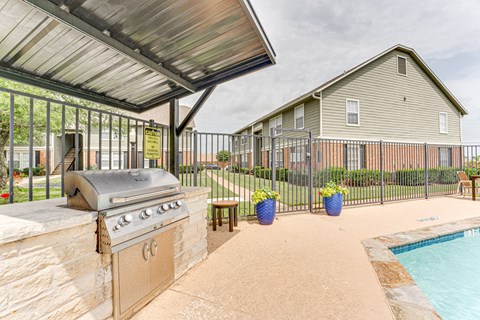A covered outdoor area with a grill and a pool.