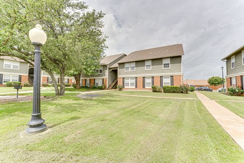 A grassy area in front of apartment buildings with a street lamp.