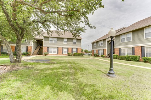 A grassy area in front of apartment buildings with a lamp post.