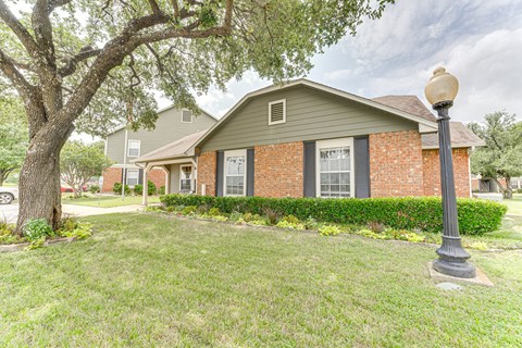 A house with a green lawn and a tree in front.