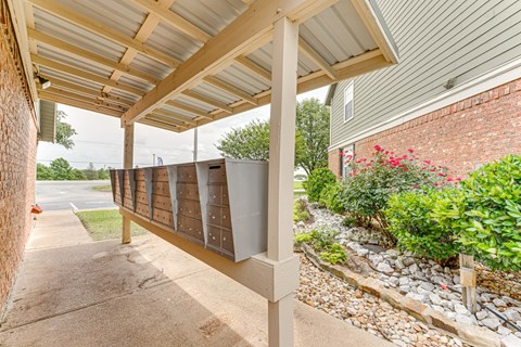 A covered walkway with a brick wall on the left and a gravel area with plants on the right.