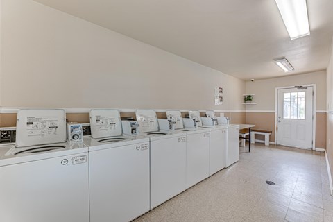 A laundromat with washers and dryers lined up.