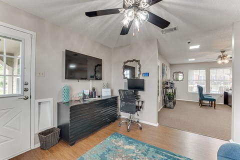 A room with a ceiling fan and a blue rug on the floor.