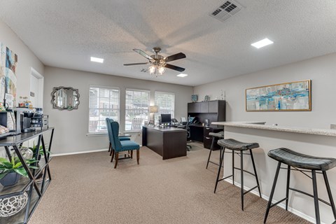 A room with a ceiling fan and a bar area.