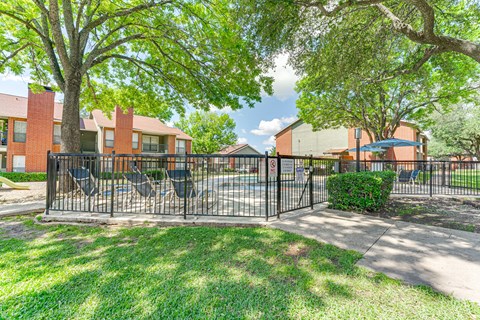 A black metal fence surrounds a green lawn at Bardin Oaks Apartments, Arlington