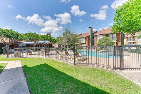 A sunny day at the poolside with a building in the background.