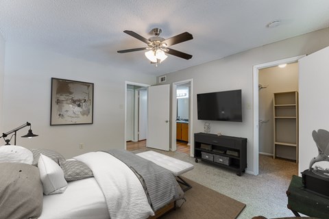 A bedroom with a large bed and a flat screen TV mounted on the wall.