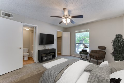 A bedroom with a bed, chair, and television at Bardin Oaks Apartments, Texas