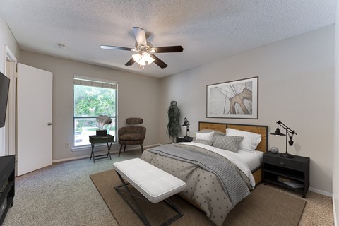 A bedroom with a bed, chair, and ceiling fan at Bardin Oaks Apartments, Arlington 76018